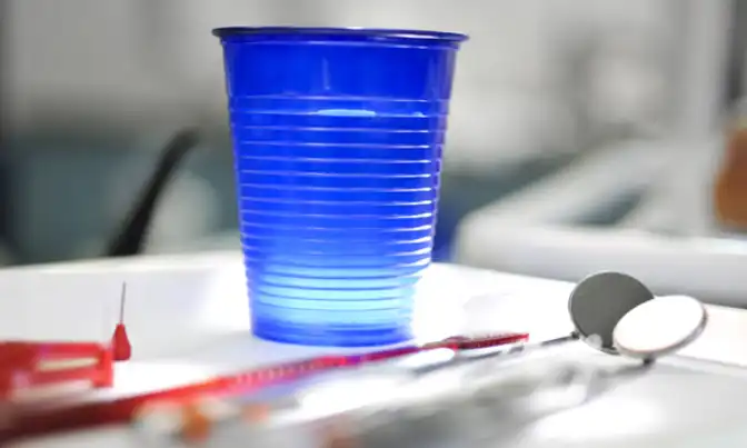 Mundspiegel und blauer Plastikbecher
