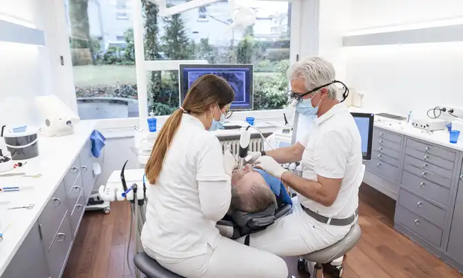 Dr. Tom Froböse und eine Mitarbeiterin während einer Zahnbehandlung